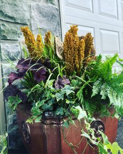 Large fall planter filled with various greenery and yellow flowers.