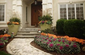 Front walk leading up to front door of home with newly landscaped flower beds and large planters.